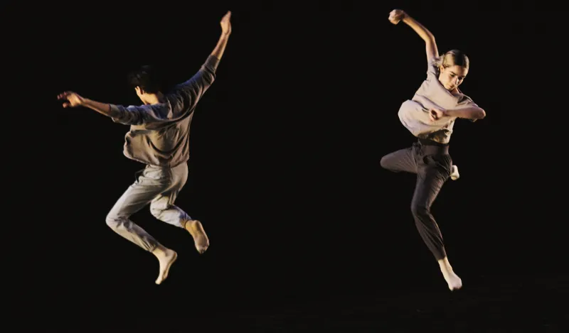 An image of two dancers from Tu Dance Compay, jumping in the air.