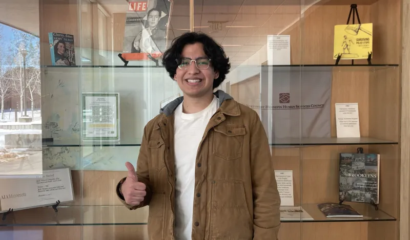 student smiling in front of bookcase