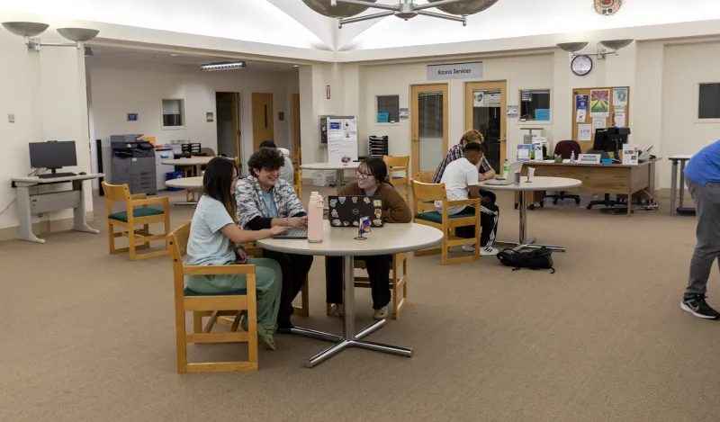 students working at a table with a tutor