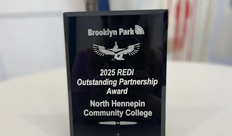 this is a photo of an award sitting on a table. The award was given to NHCC from the City of Brooklyn Park. It was the 2025 REDI Outstanding Partnerships Award. 