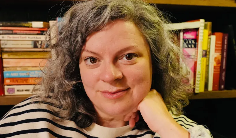 this is a headshot photo of NHCC faculty, Kelly Lundquist taken in front of a bookcase. 
