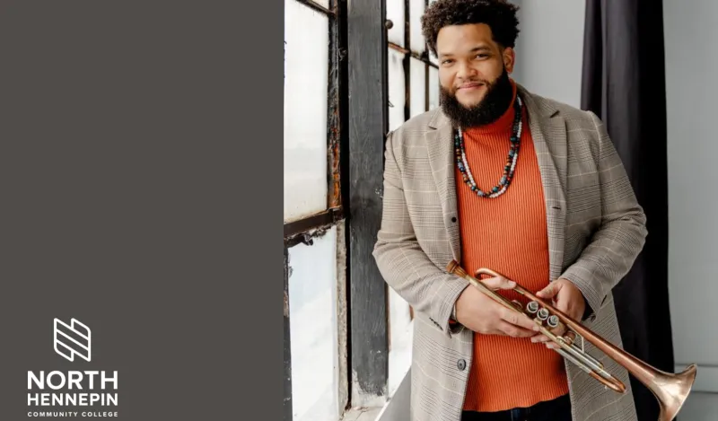 this is a headshot photo of jazz musician, Kris Johnson holding his trumpet and standing near a window.  