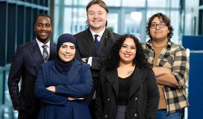this is a photo of the five, spring 2026 Kappa Beta Delta Officers, Exocee, Noah, Juan, Muna and Norma all smiling and facing the camera for a photo. 