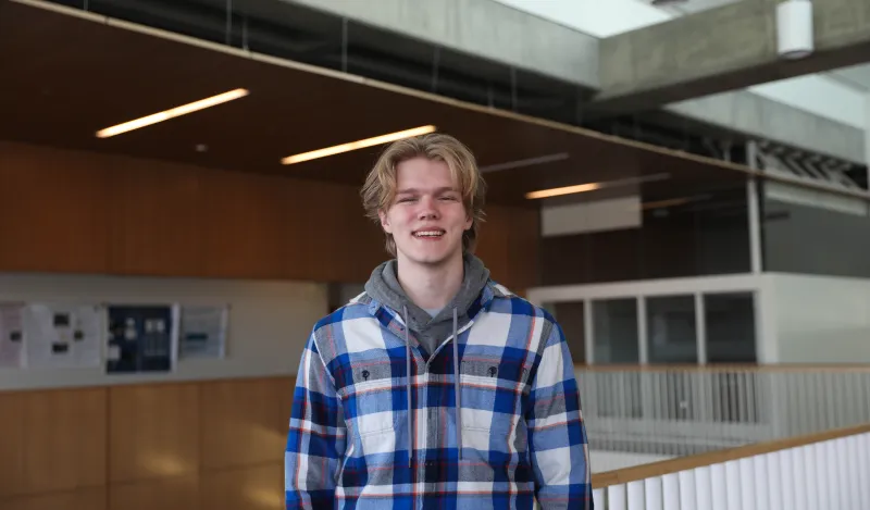 this is a photo of former NHCC student, Casey Hjelmstad, standing near the top of the staircase in NHCC's BHCC building, smiling at the camera. 