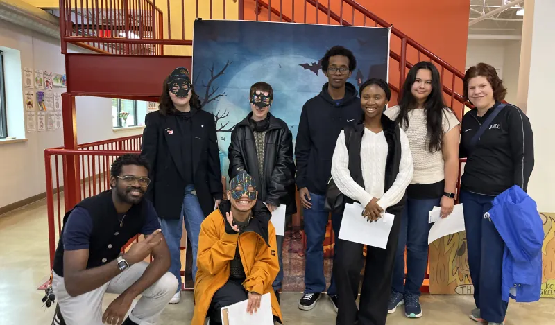 group of Biology Club with Halloween Masks standing in front of a stairwell and backdrop