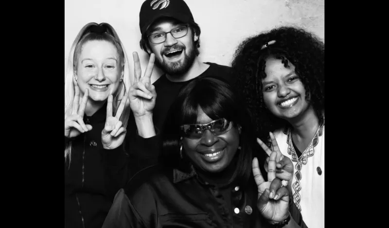 this is a black and white photobooth photo of four NHCC students smiling for the camera. 