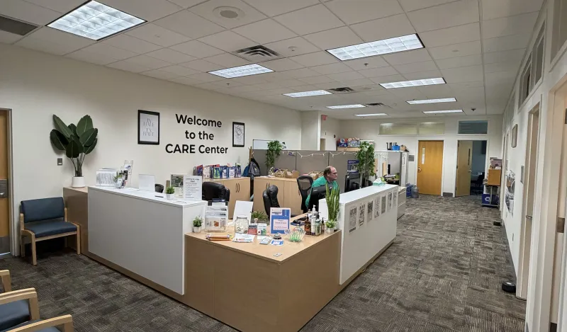 this is a photo of the CARE Center Office with administrative assistant, male NHCC employee, Kory sitting at the desk, looking at his computer. 