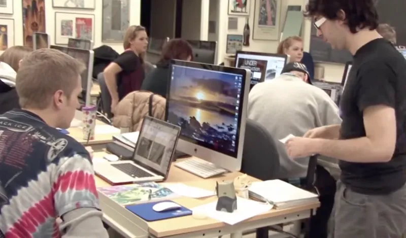 students talking and working at computers in a classroom