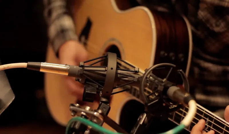 student strumming guitar with a microphone near by 