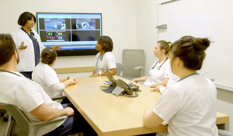 nursing students in a lap talking with an instructor 