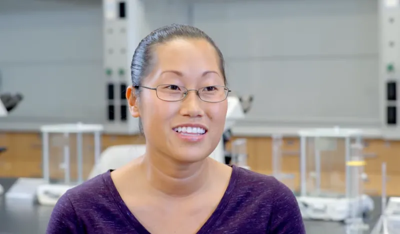 Woman smiling with lab equipment in the background