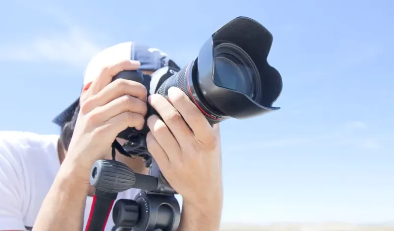 student looking through a dslr camera 