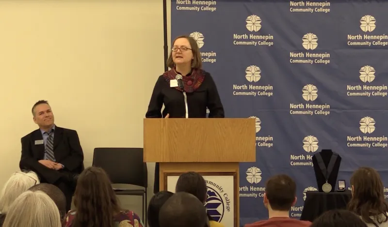 woman talking at a podium to crowd