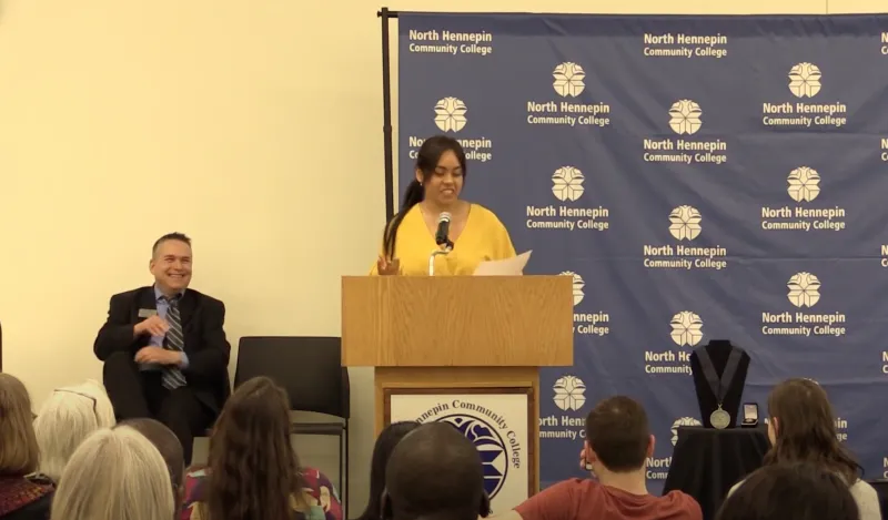 woman standing at podium addressing gathered crowd