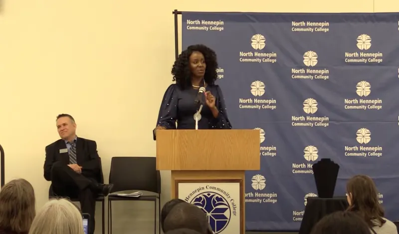 woman standing at podium addressing gathered crowd