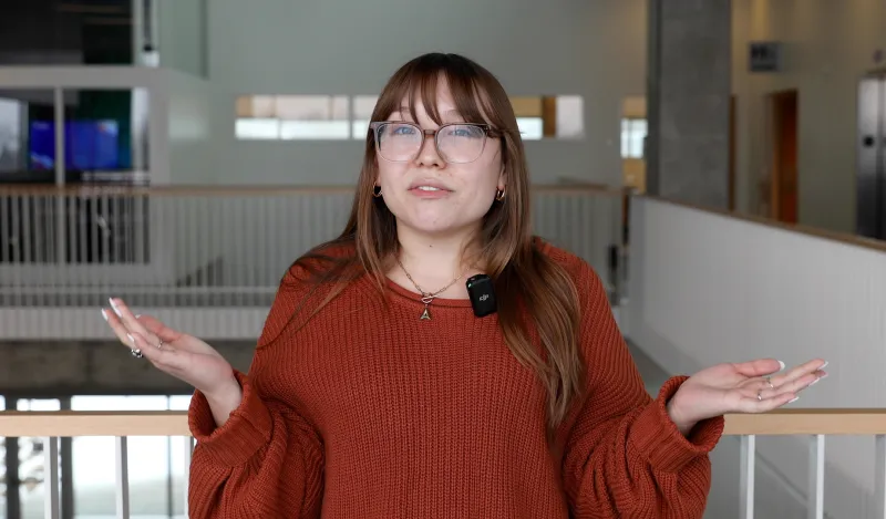 woman wearing glasses and talking in a large room 