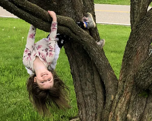 digital photography by Gabrielle Johnson of a little girl hand by her hands and feet from a low hanging tree branch