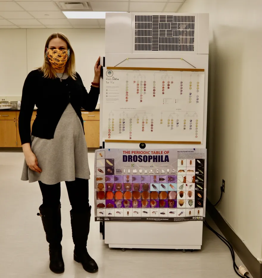 nursing student Melissa Sawyer standing next to a lab fridge with nursing posters and charts on its side