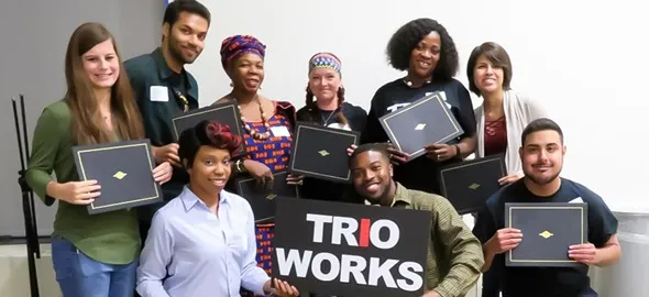 students smiling holding a sign that says trio works 