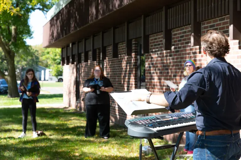 faculty member outside with students rehearsing 