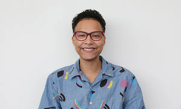 student with glass smiling with a white background