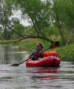 women paddling a kayak down a river