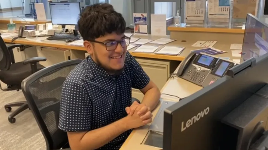 male student sitting at a desk smiling