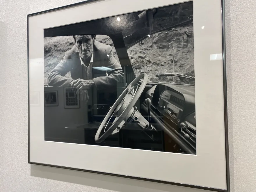 a black and white photo of a man leaning inside a car window