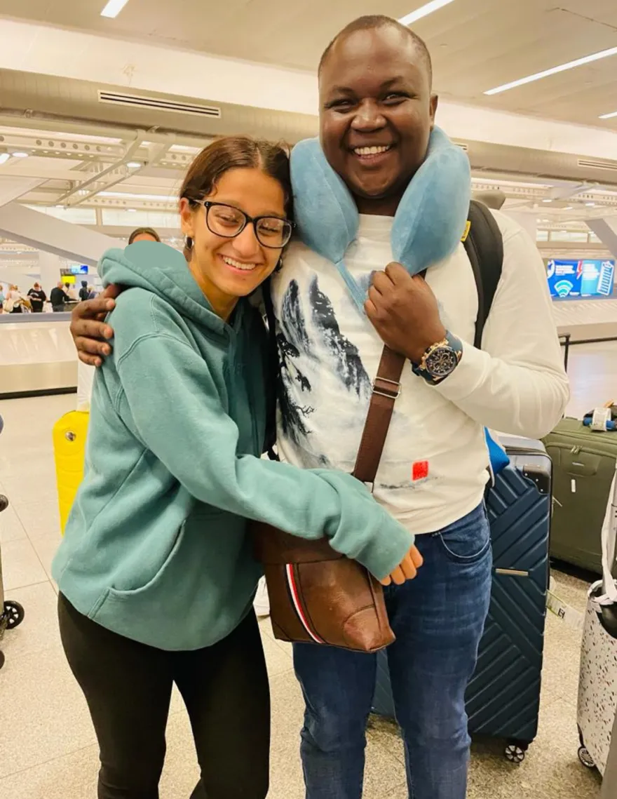 a photo of NHCC student, Donald Agik and friend smiling at the airport going back to the U.S.