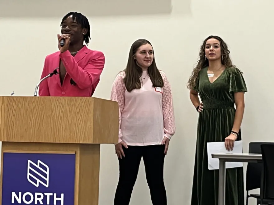 a photo of a student in a pink blazer speaking in the Grand Hall