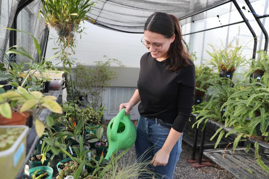 NHCC student, Aviel watering plants in the Tessman Greenhouse