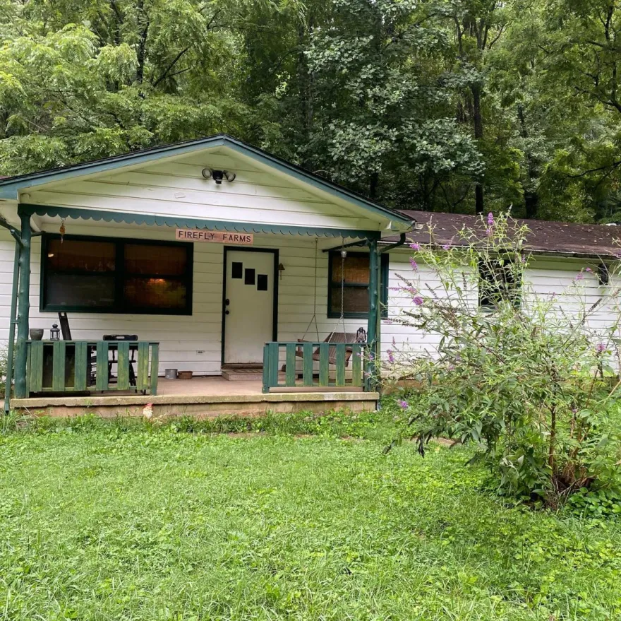 a photo of a white barn-house at Firefly Farm in grassy Tennessee