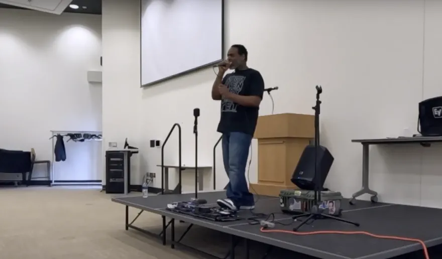 a man sings with a microphone at NHCC on a stage