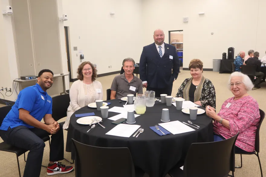 a photo of current NHCC staff with retirees sitting at a table smiling