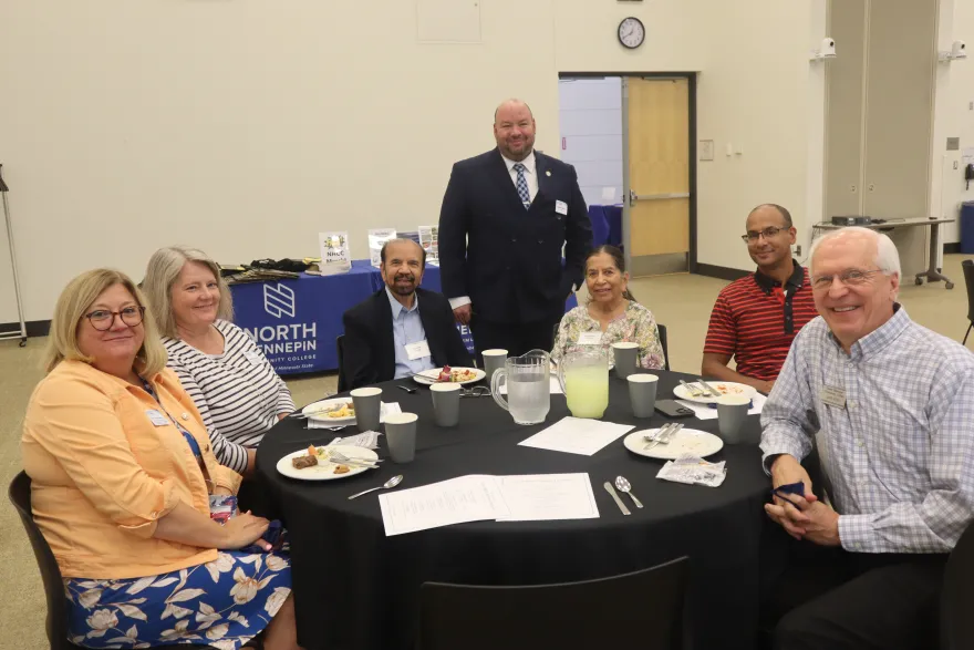 a photo of current NHCC staff with retirees sitting at a table smiling