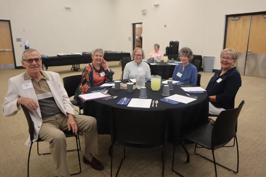 a photo of retirees sitting at a table together smiling 