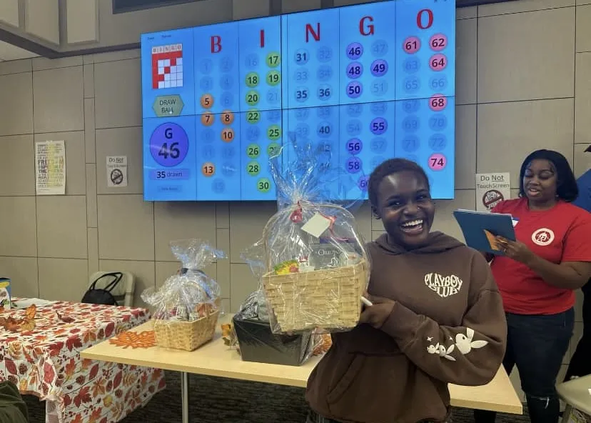 A photo of a girl smiling in the Campus Center after winning her prize playing Bingo