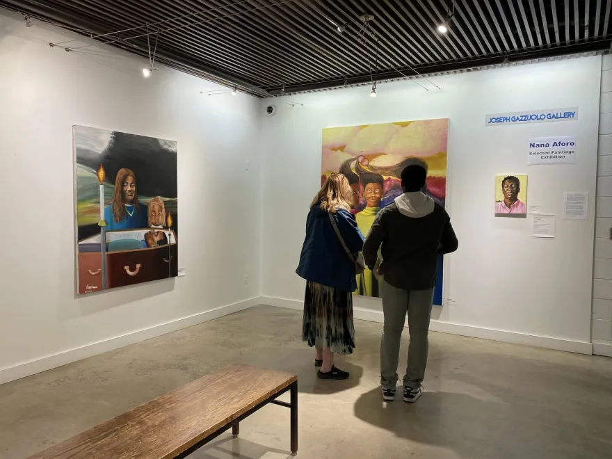 a photo of two people in the Art Gallery with their backs to the camera looking at paintings on the wall. 