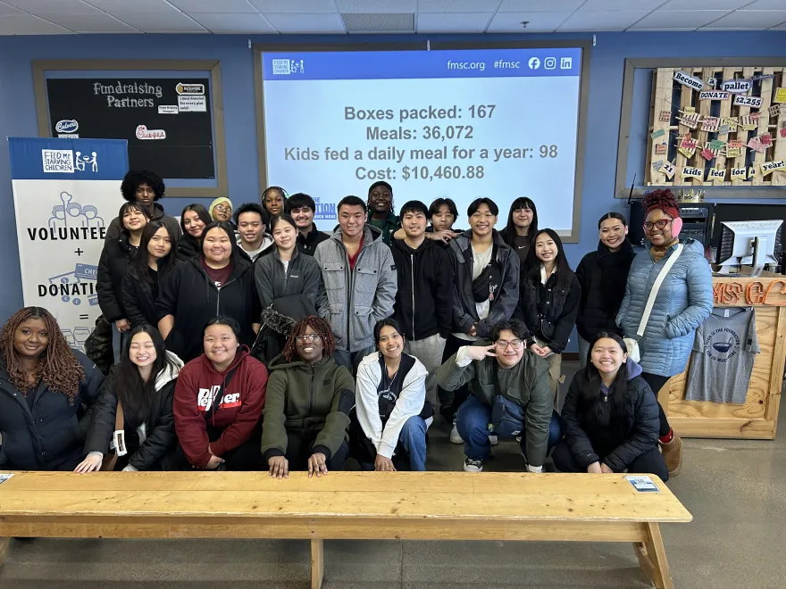 a group photo of Upward Bound students smiling before volunteering at Feed My Starving Children