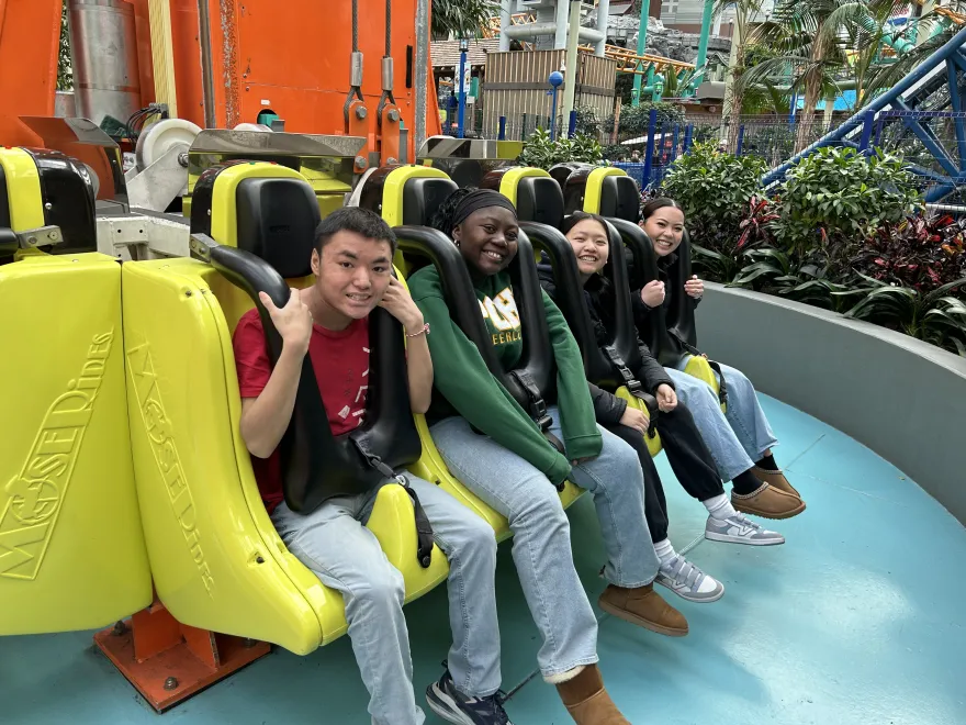 a photo of three Upward Bound students on a ride at an amusement park