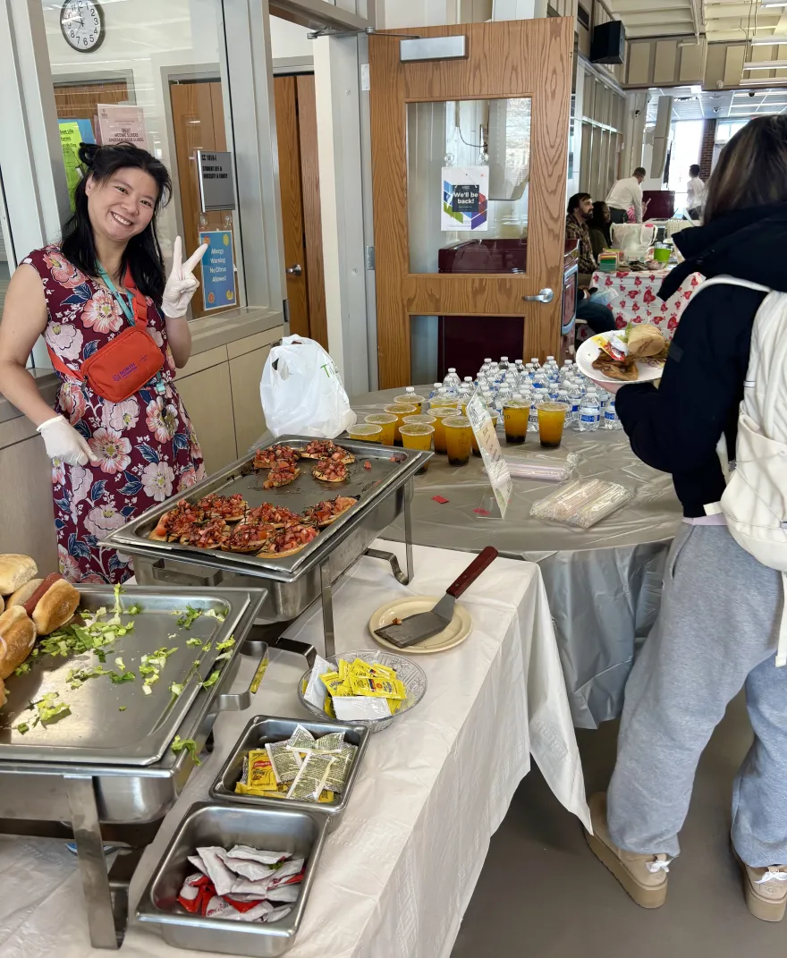 a photo of NHCC staff member, Hanh Le serving a student food at a Campus Center event. 