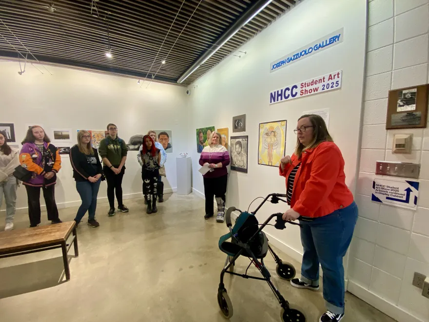 This is a photo of special guest art juror, Liz, speaking to students at the Student Art Show Reception. 