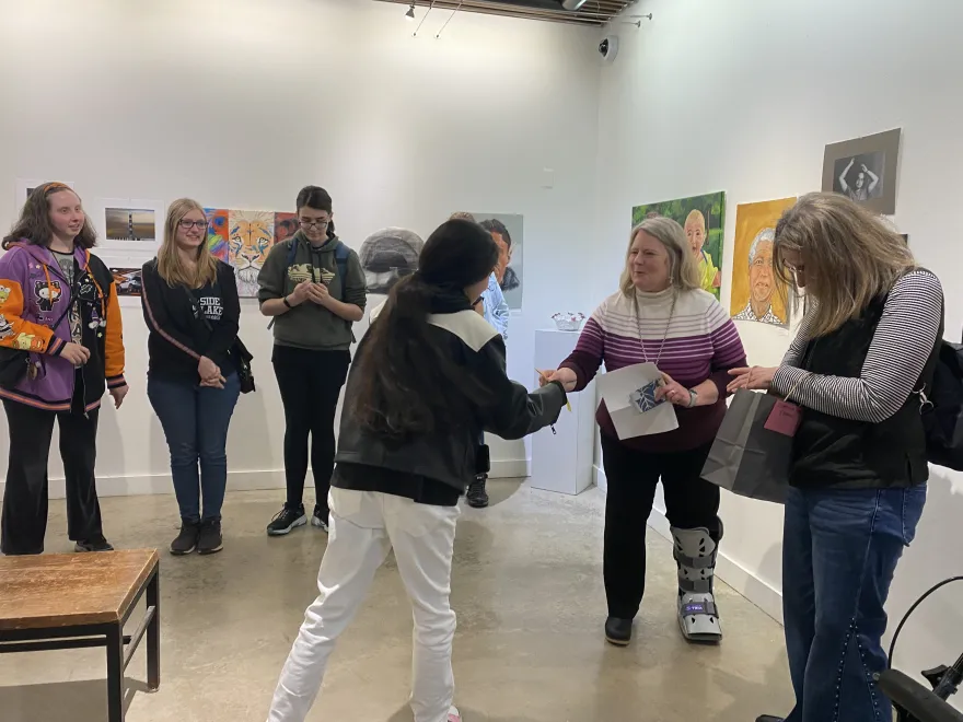 This is a photo of NHCC student, Johanna Vicente receiving an award ribbon at the 2025 Student Art Show. 