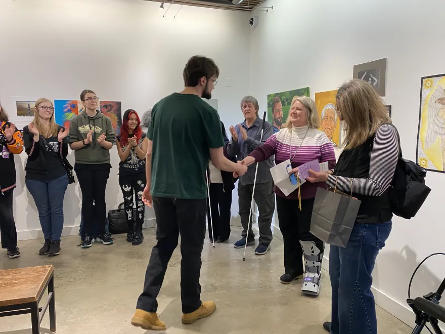 This is a photo of NHCC student, Nicholas Ochetti receiving an award ribbon at the 2025 Student Art Show.