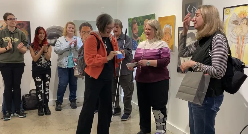 This is a photo of NHCC student, Robin Langevin receiving the People’s Choice Award at the 2025 Student Art Show.