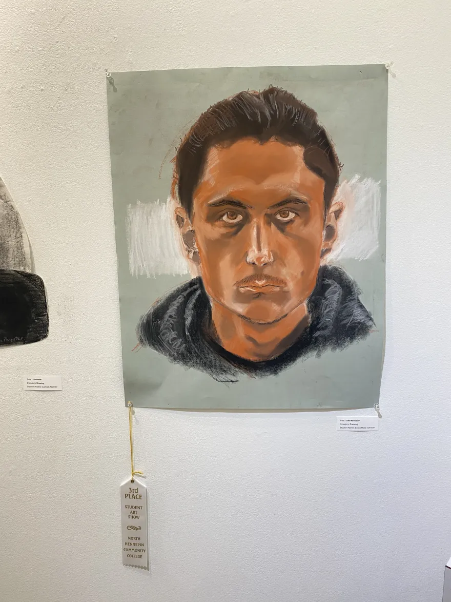 This is a photo of a drawing that received an award ribbon at the NHCC Student Art Show, titled, "Self-Portrait.”
