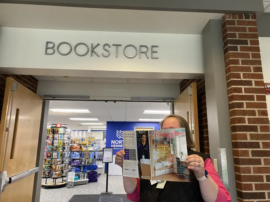 this is a photo of Bookstore Director Traci Hildebrandt-Smith standing outside of the Bookstore holding the magazine that she was featured in while standing in front of the Bookstore. 