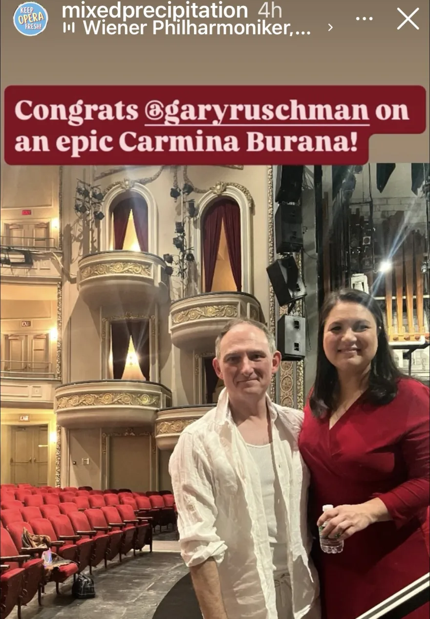 This is an Instagram screenshot from Mixed Precipitation's account of a post-performance photo of Gary Ruschman with a friend from a recent production, the photo also features a historic theater space in the Twin Cities. The text reads, "Congrats, Gary Ruschman on an epic Carmina Burana.”