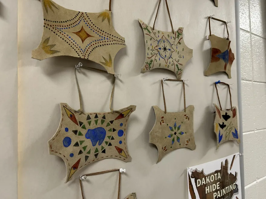 this is a photo of six student created paintings on animal hides hanging to dry. 
