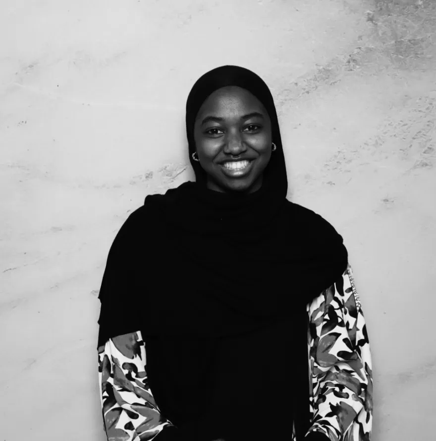 this is a black and white photobooth photo of NHCC student, Nurah smiling and holding up her Student Life Award certificate.